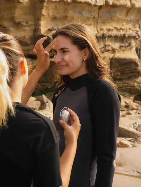 Two surfers in wetsuits smiling after a session